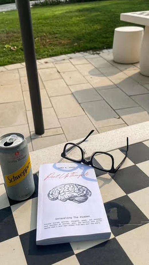 Pent Up Thoughts paperback by James B. Agape resting outdoors, healing poetry for anxiety and self-worth